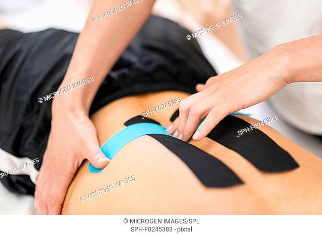 Physical therapist placing kinesio tape on patient's back