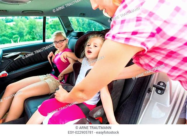 Mutter schnallt Kind im Auto Kindersitz an