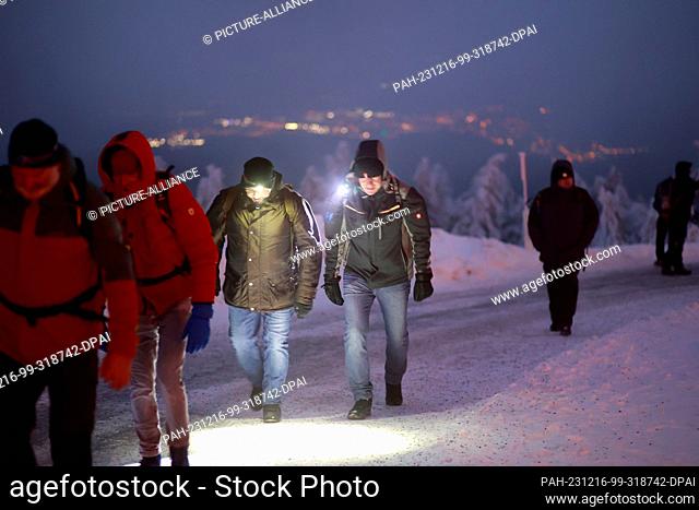 16 December 2023, Saxony-Anhalt, Schierke: Hikers walk over the Brocken during the Brocken breakfast with geocaching in the early hours of the morning