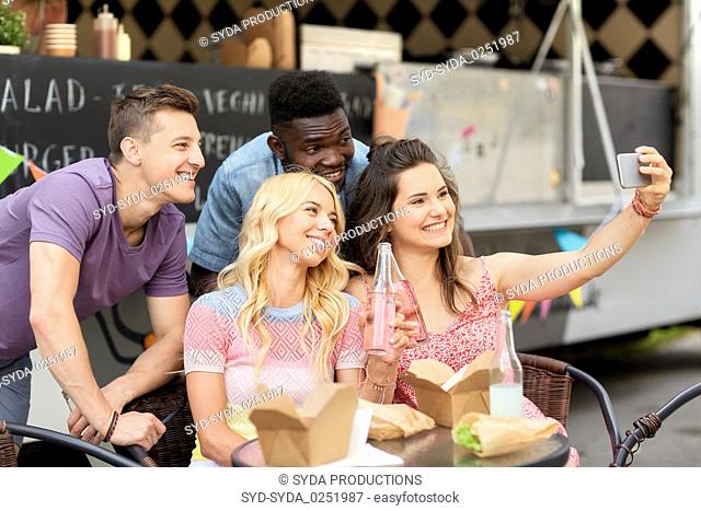happy young friends taking selfie at food truck