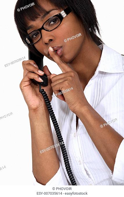 woman on the phone making a sign for silence