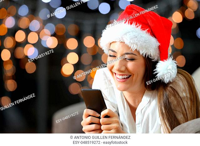 Woman texting on phone on chritmas sitting on a couch in the living room at home