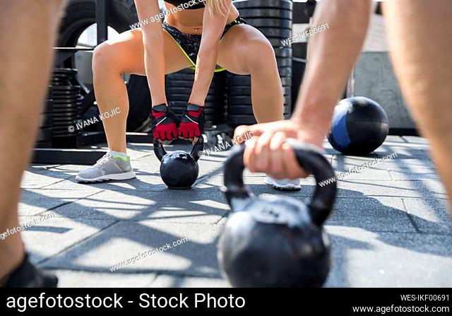 Friends exercising with kettlebells at rooftop gym