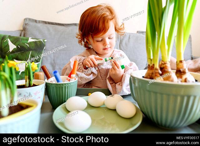 Girl coloring egg during Easter at home