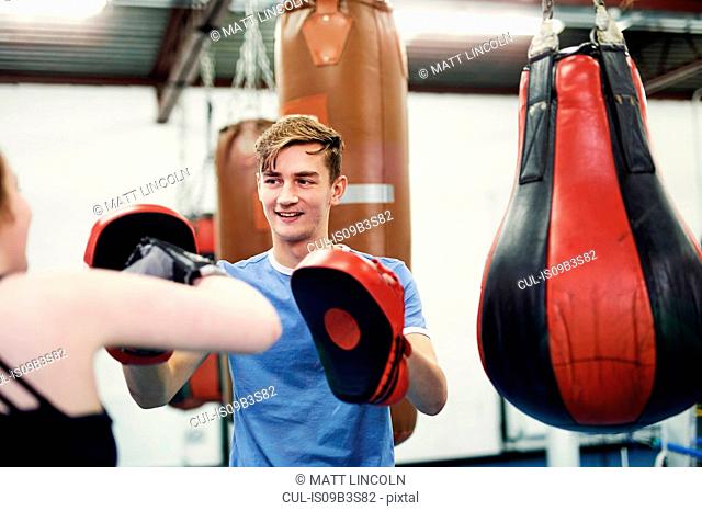 Female boxer training, punching teammate's punch mitt