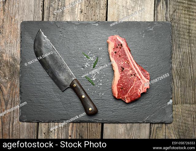 fresh raw piece of beef meat, striploin steak on a wooden background, top view. Marbled piece of meat New York
