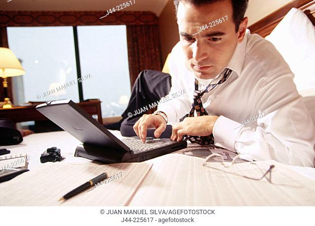 Businessman working with laptop computer on the bed in a hotel room