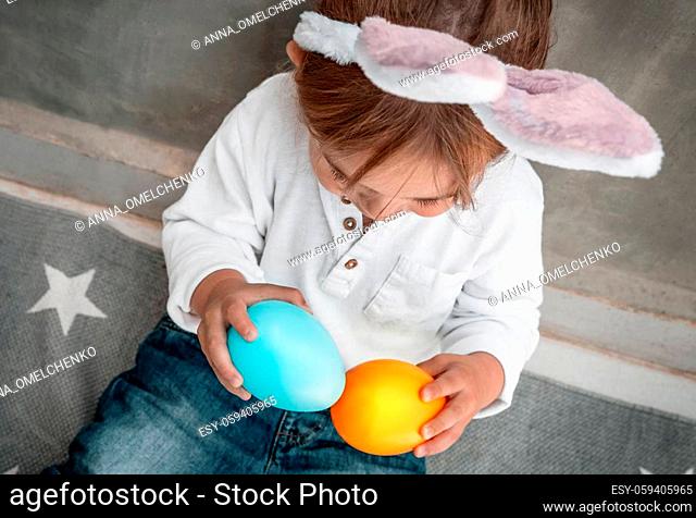Cute Little Baby Dressed as Festive Bunny Playing with Colorful Decorative Eggs. Enjoying Happy Easter Holiday. Great Christianity Holiday