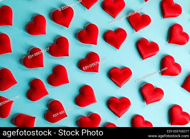 Valentine's day many red silk hearts on blue paper background, love concept