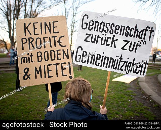 15 April 2021, Hamburg: A woman holds two signs reading ""No profits with land and rent!"" and ""Cooperatives back to non-profit status"" during a rally of the...