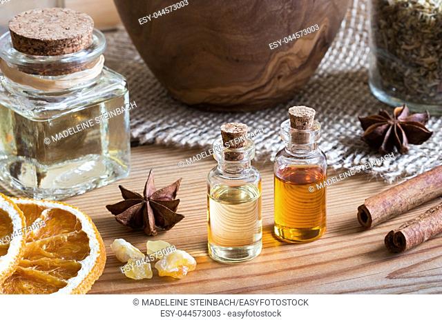 Bottles of essential oil with star anise, cinnamon, frankincense and dried orange slices