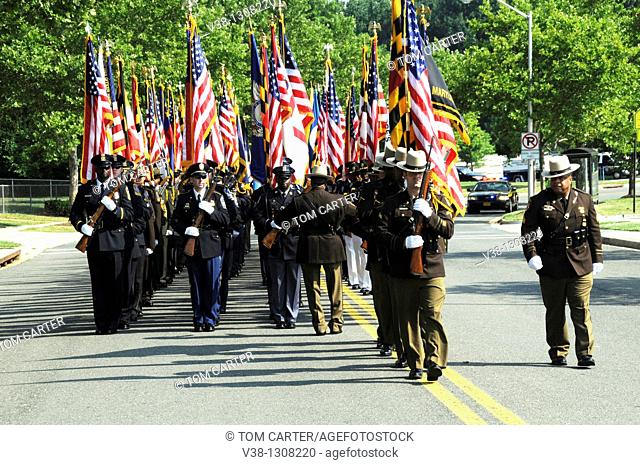 Hundreds of police departments honor guard march down the street at the funeral for a Maryland State Police Trooper in Lahnam, Maryland