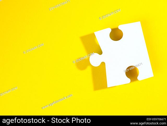 large blank white paper puzzle with shadow on yellow background, top view. Abstract creative backdrop for designer
