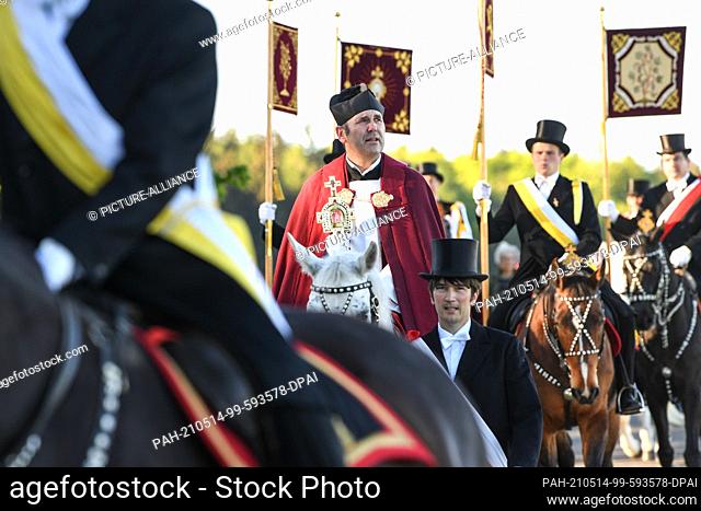 14 May 2021, Baden-Wuerttemberg, Weingarten: Dean Ekkehard Schmid (center), the rider of the Holy Blood, holds the relic of the Holy Blood on a white horse