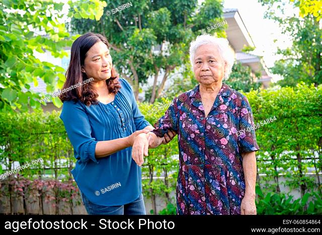 Asian elderly woman with caregiver walking with happy in nature park
