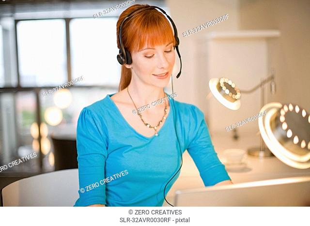 Businesswoman in headset using laptop