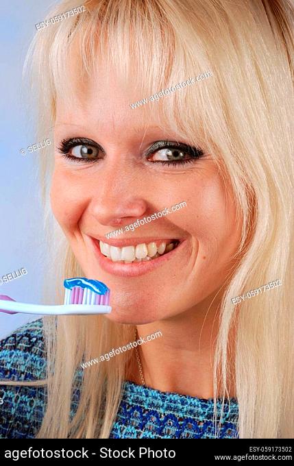 Young blonde woman brushing her teeth