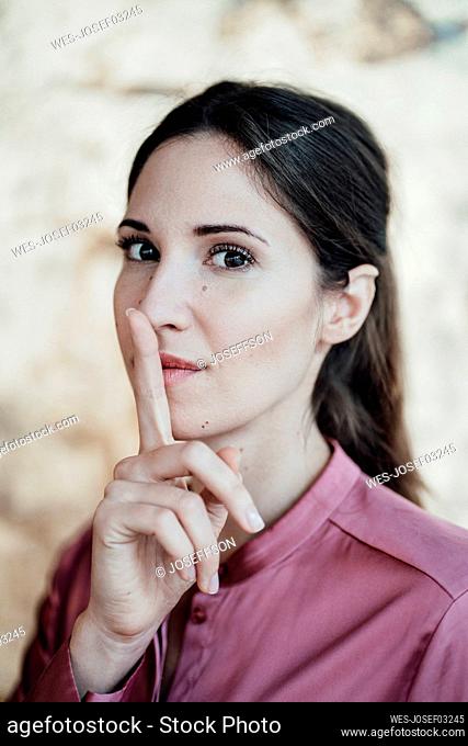 Businesswoman with finger on lips at cafe