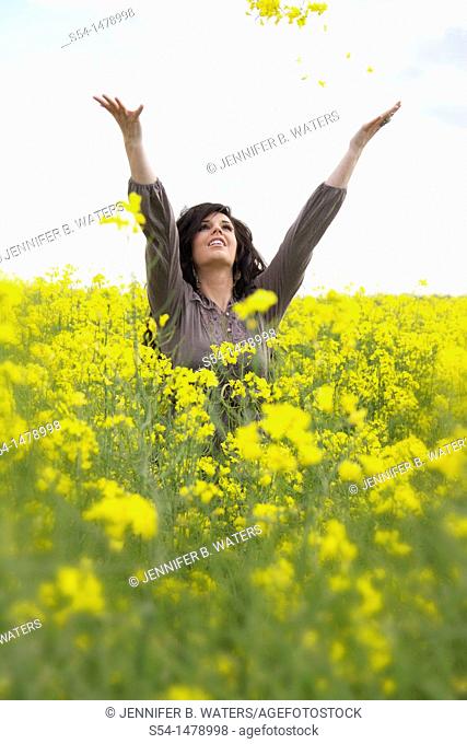A happy young caucasian woman in a field of canola
