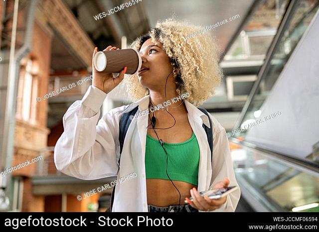 Contemplative woman drinking coffee from disposable cup