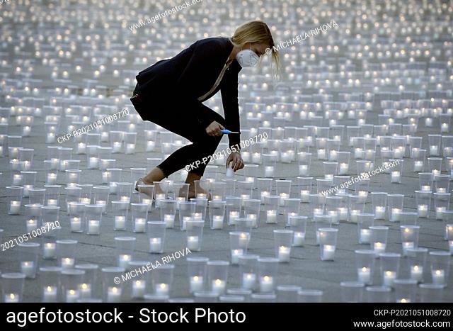 A woman lights candles during the commemorative event for COVID-19 victims at the Prague Castle, Czech Republic, May 10, 2021