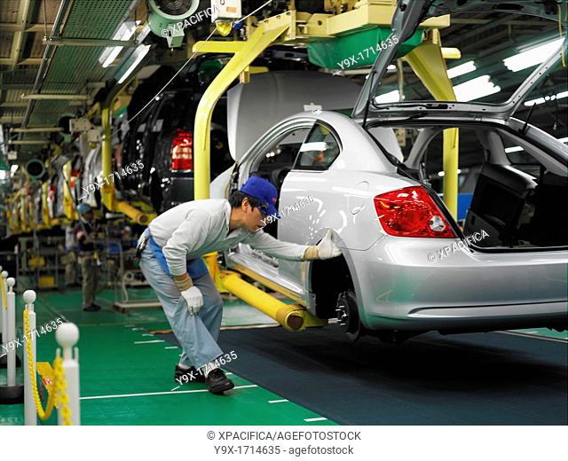 Factory workers producing the hybrid Toyota Prius cars, work on the assembly line at the Toyota City factory in Japan. Here a Scion TC is being inspected