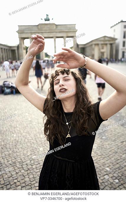 loose young woman dancing with closed eyes at Brandenburg Gate, in Berlin, Germany