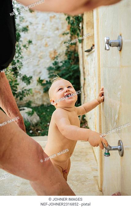 Little boy taking shower outdoors