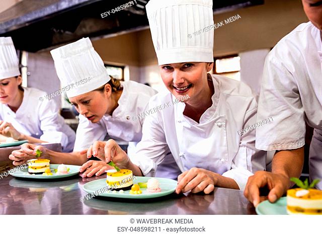 Group of chefs garnishing delicious desserts in a plate