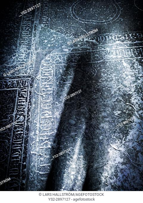 Scary shadow on old grave stone in church. Concept of death, crime and horror