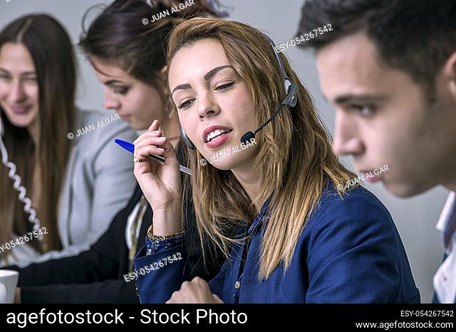 Young woman sitting and communicating in the call center during the work. Horizontal indoors shot