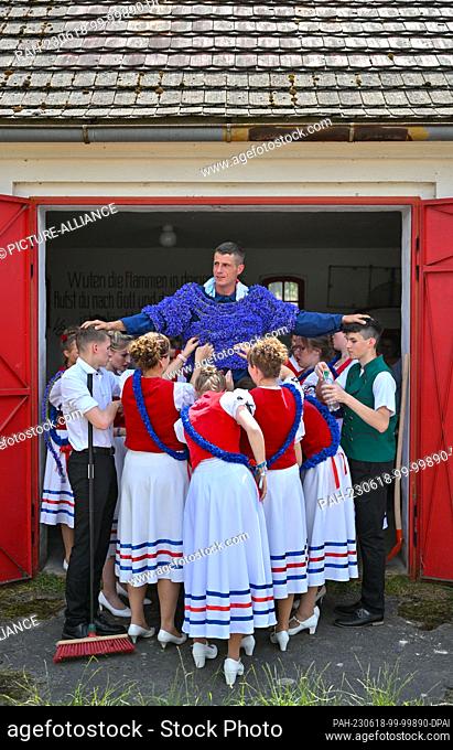 18 June 2023, Brandenburg, Casel: Tobias Richter, who is St. John this year, is decorated with cornflowers by girls. The St