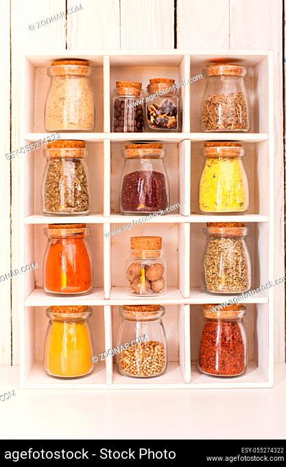 Assortment of dry spices in vintage glass bottles in wooden box