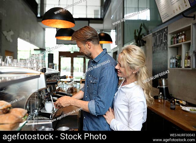 Coffee shop owners using espresso machine in cafe