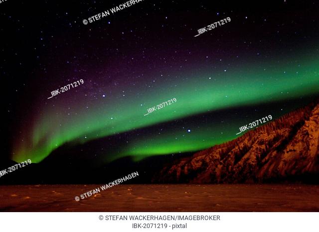 Northern lights, Polar aurora or Aurora Borealis, green, over frozen Yukon River, Dawson City facing Moose Hide, Yukon Territory, Canada