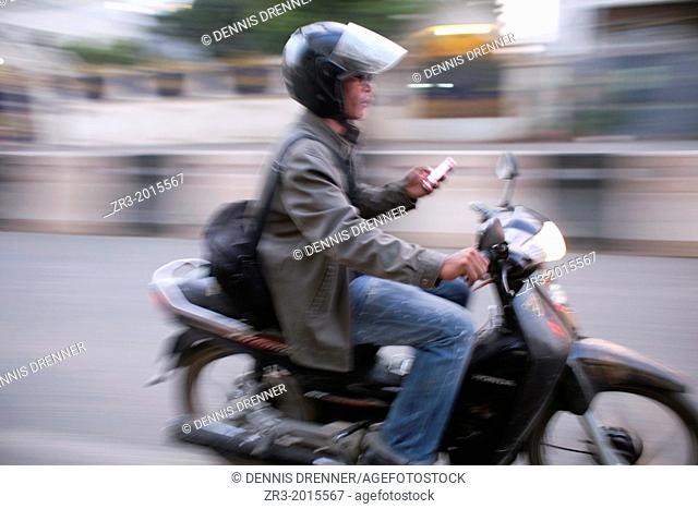 A motorcycle rider checks his smartphone in Phnom Penh, Cambodia