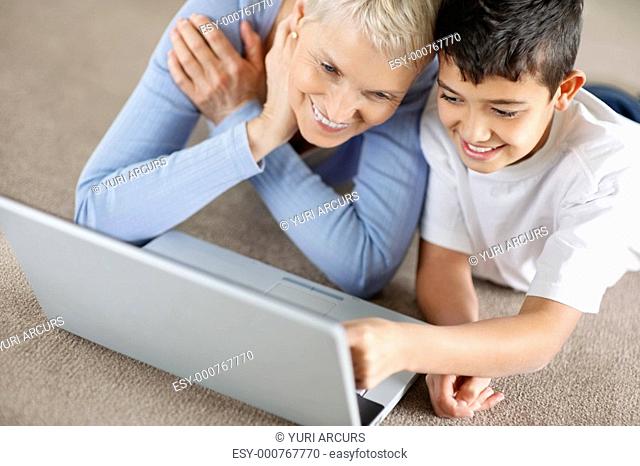 Portrait of a grandson and grandmother browsing the internet on floor