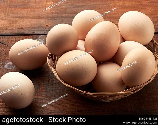 raw brown chicken eggs in a wooden plate on the table, top view