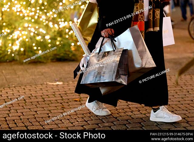 PRODUCTION - 15 December 2023, North Rhine-Westphalia, Cologne: A woman carries shopping bags in the Schildergasse pedestrian zone