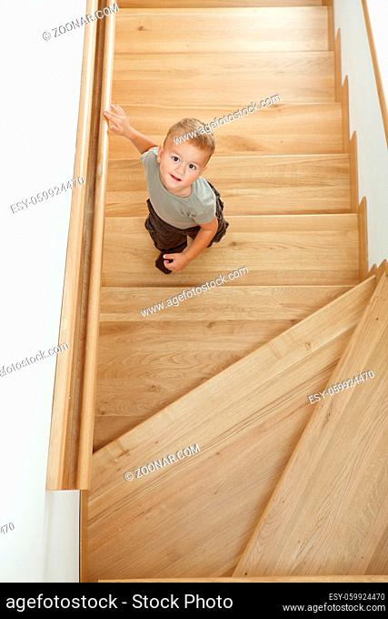 Little boy standing on stairs, looking up. Overhead shot