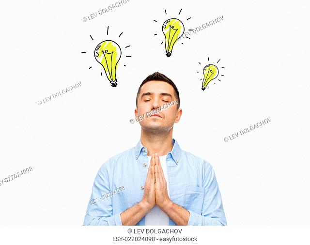 inspiration and people concept - man with closed eyes praying god for inspiration with lighting bulb doodles