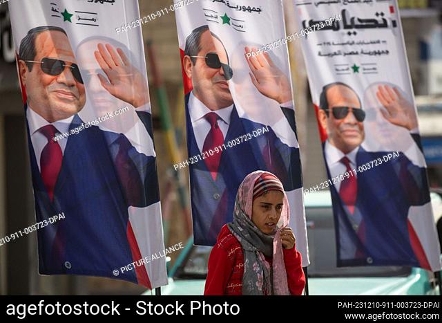 10 December 2023, Egypt, El-Arish: A woman walks past posters of the President of Egypt and presidential candidate Abdel Fattah El-Sisi in El-Arish, North Sinai