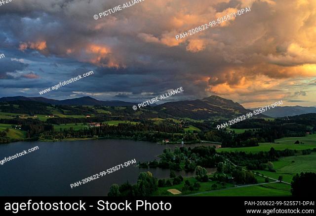 22 June 2020, Bavaria, Moosbach: The light of the setting sun colours the sky above the Rottachsee and the Grünten (aerial photo with a drone)