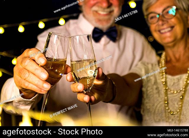 couple of two old and mature seniors enjoying and having fun together celebrating the new year night drinking and clinking with champagne