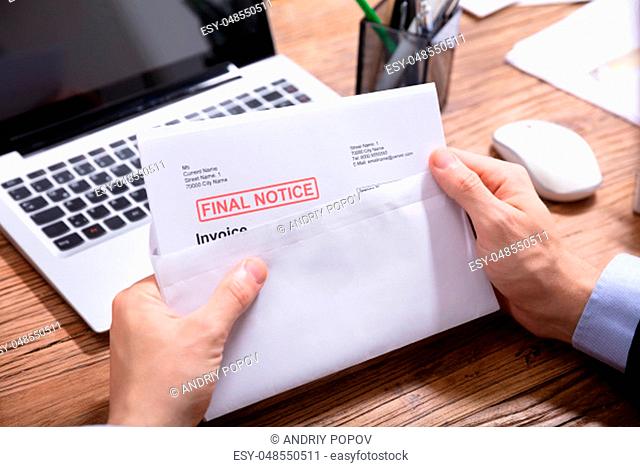 Close-up Of A Person's Hand Opening The Envelope With Final Notice Invoice In It