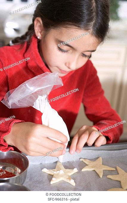 Girl icing biscuits with piping bag