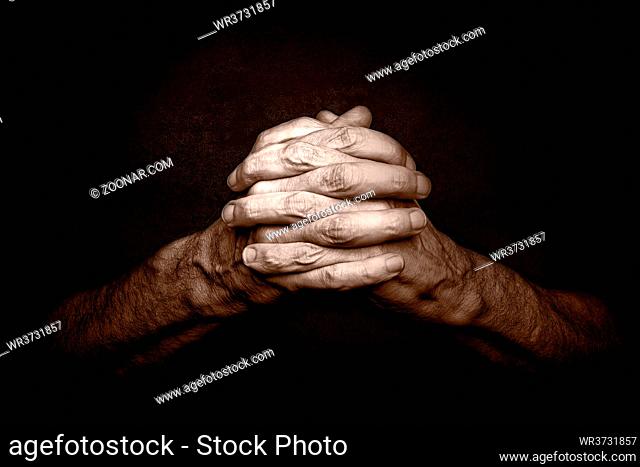 Man's Hands with crossed fingers. This is a classical gesture of a person praying God in the christian religions