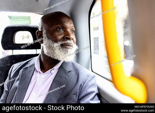 Senior businessman with beard looking through taxi window