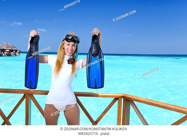 The young pretty woman in equipment for a snorkeling on the sundeck over the sea. Maldives