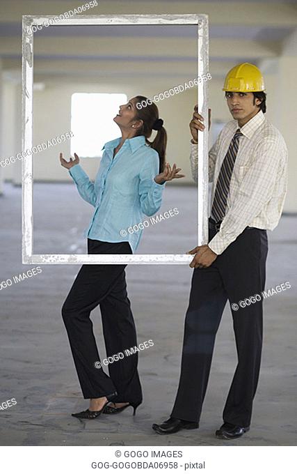 Businessman holding empty frame around woman